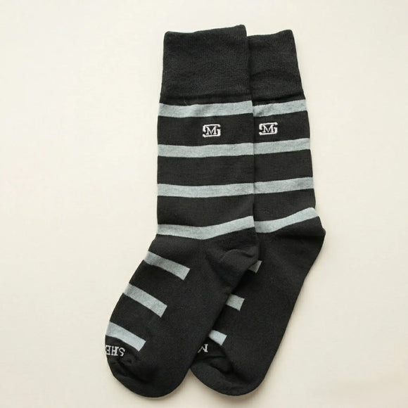 Par de calcetas para hombre negras con franjas horizontales grises, diseño casual de algodón con logotipo 'SM' bordado y nombre de marca Sherman Morgan en la punta.