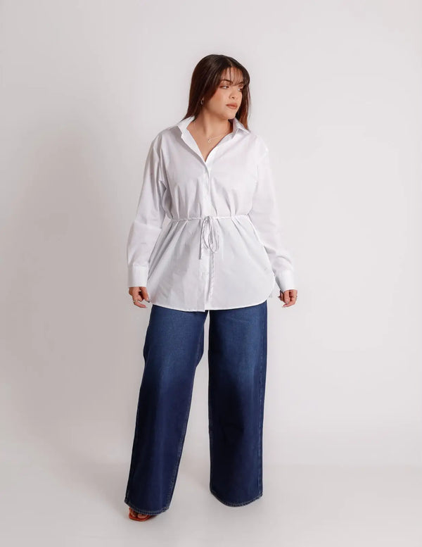 Camisa oversize blanca con listón, vista frontal en modelo, listón amarrado en cintura