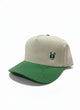 Vista lateral de gorra para hombre color beige con visera verde contrastante, detalle de parche ZAK bordado y perfil estructurado.