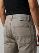 Vista posterior de jeans para hombre con etiqueta de marca en vinipiel gris, placa metálica distintiva y bolsillos con diseño de franja horizontal.