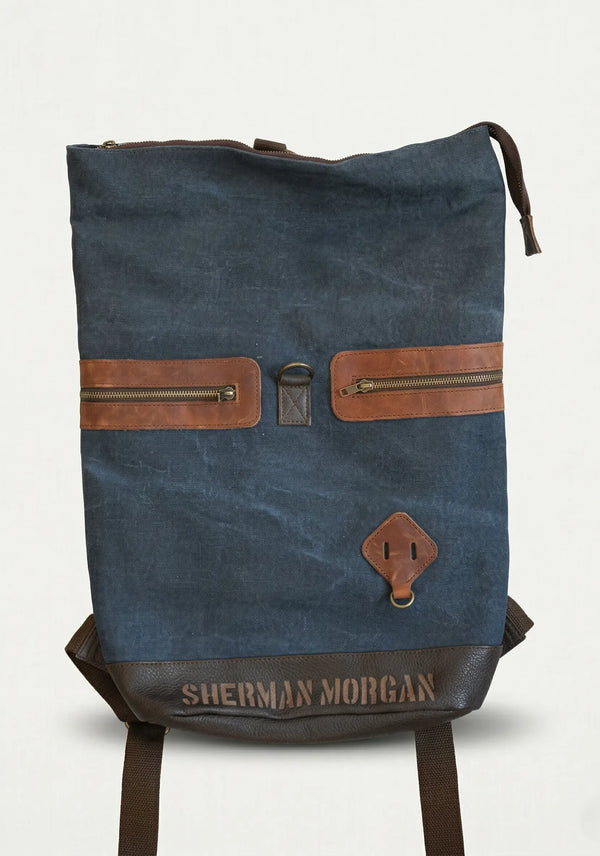Mochila Sherman Morgan de lona encerada azul marino con detalles en vinipiel café, diseño casual con múltiples bolsillos y correas ajustables.