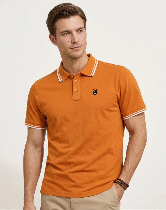 Polo naranja para hombre con filos blancos en cuello y mangas, logo bordado de perro Boston Terrier Zak, Sherman Morgan.